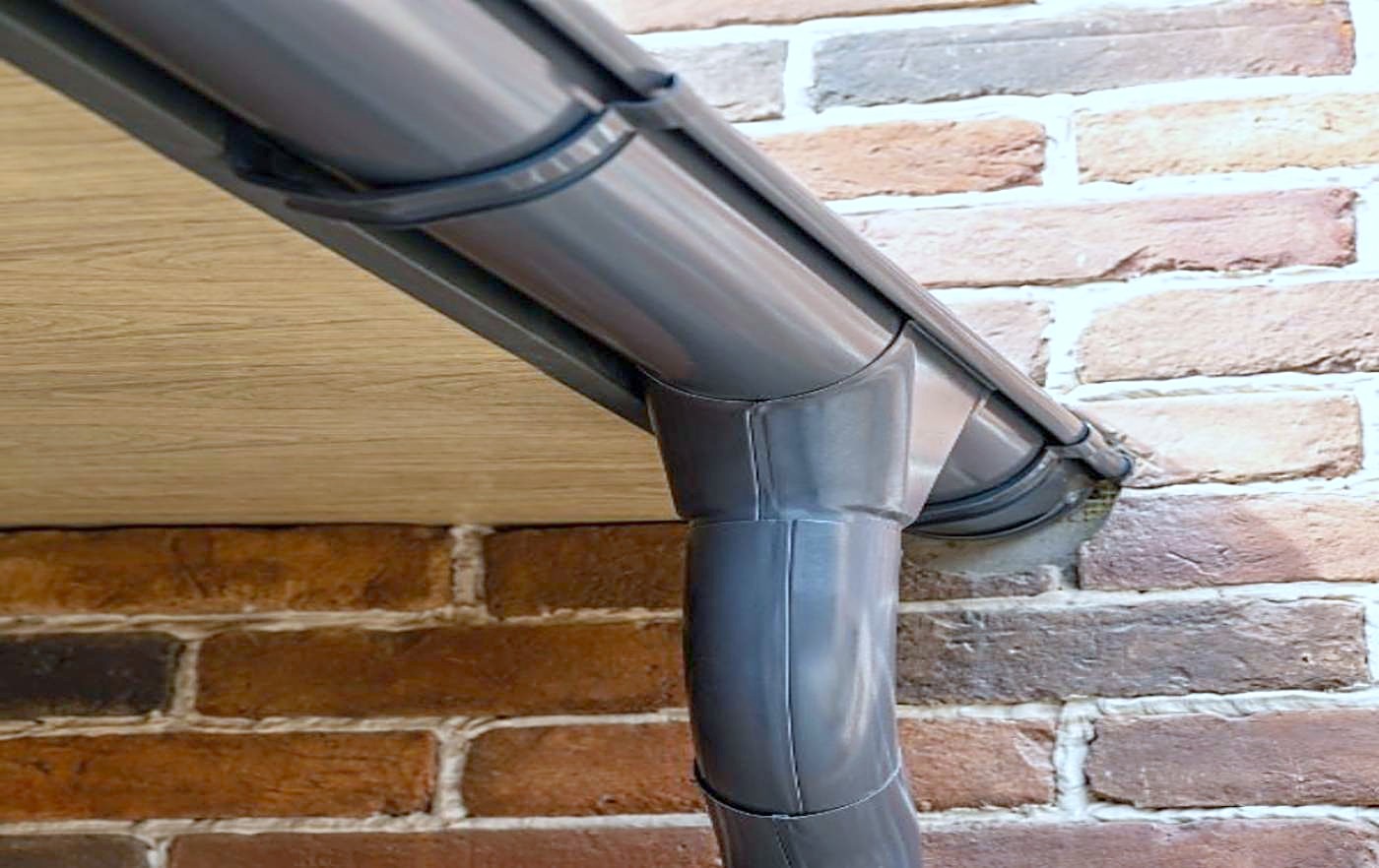 A black gutter and downspout against brick