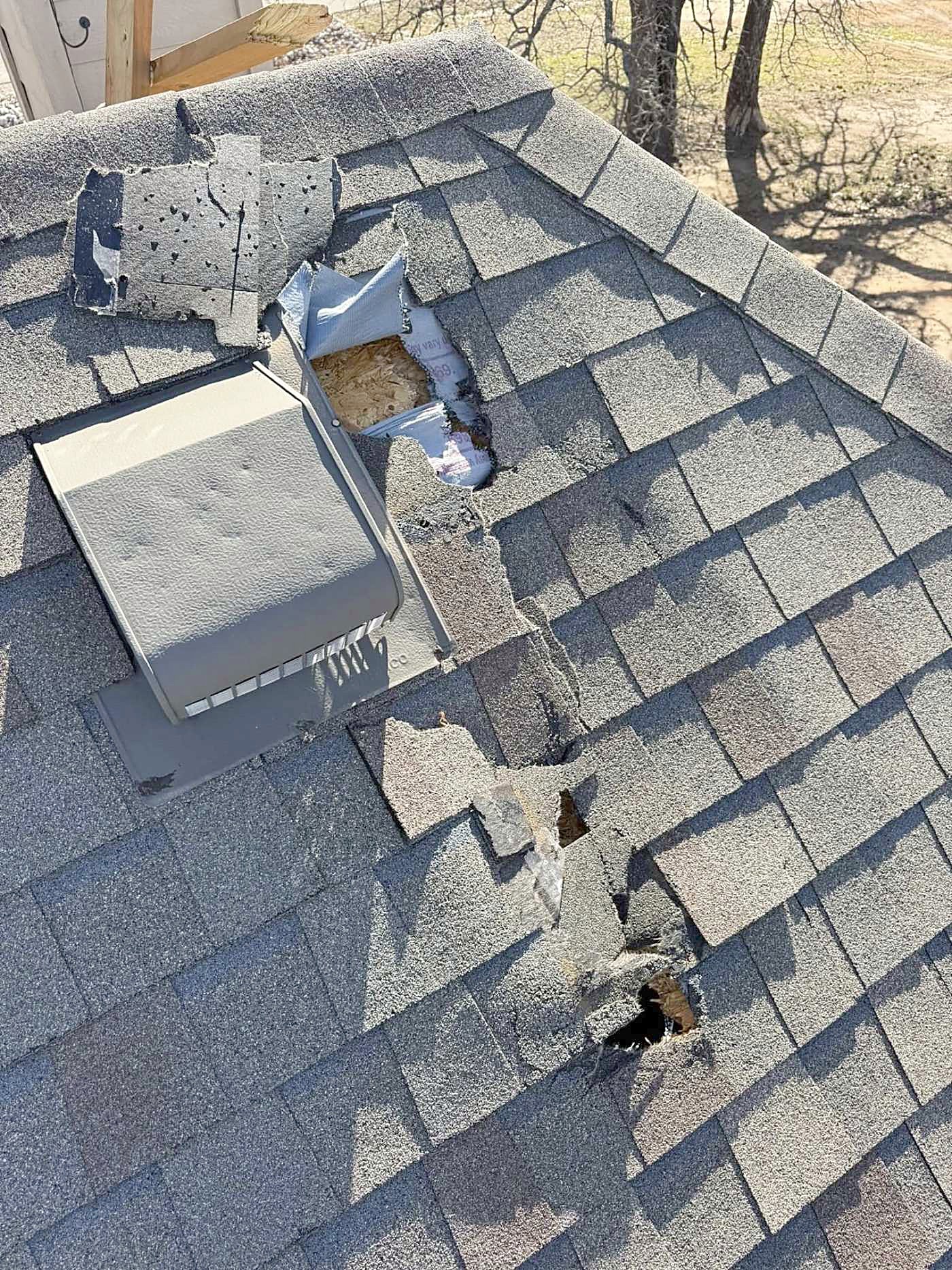 Hail-damaged shingles around a roof vent
