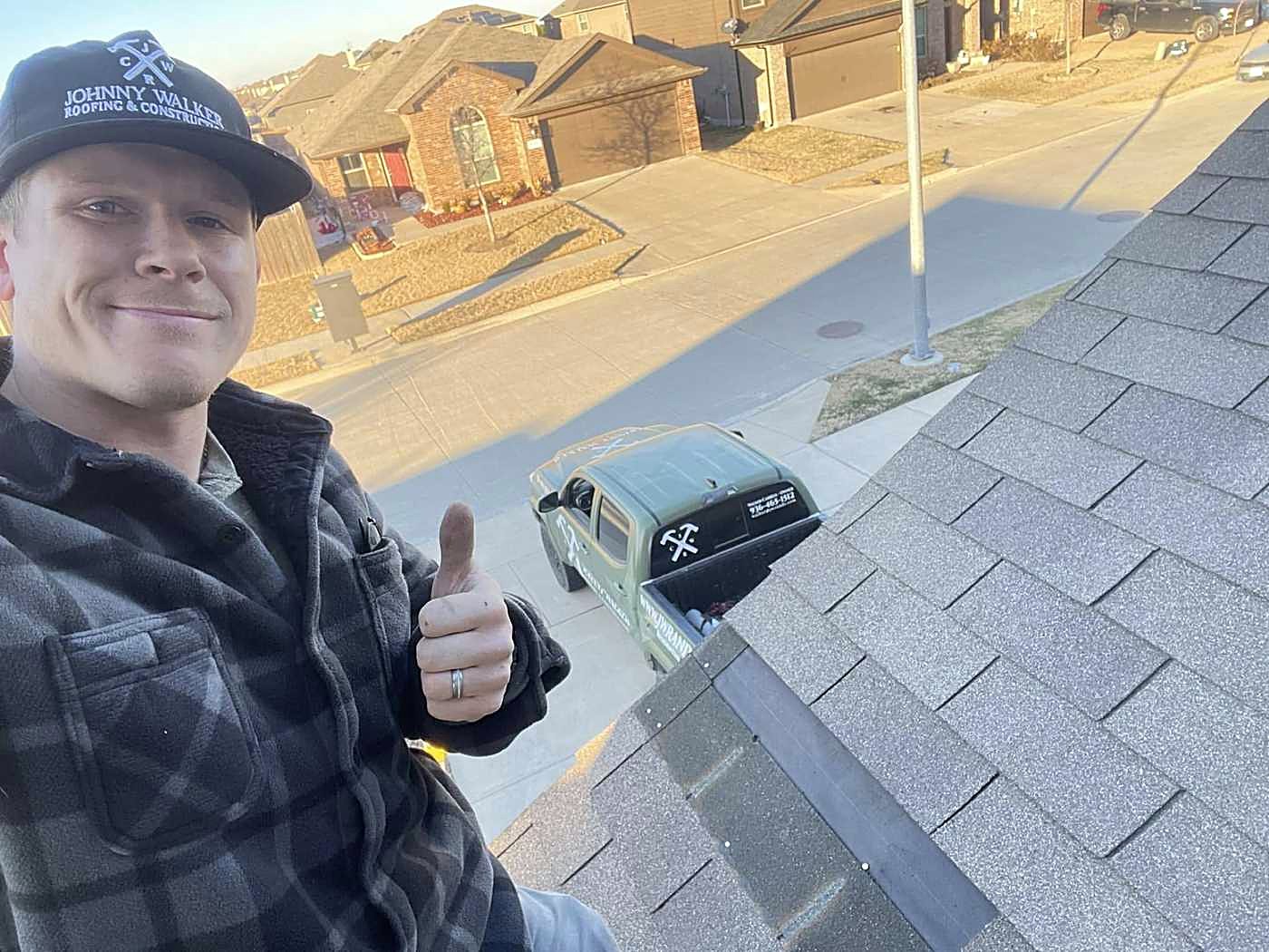 A Johnny Walker roofer giving a thumbs up from a shingle roof